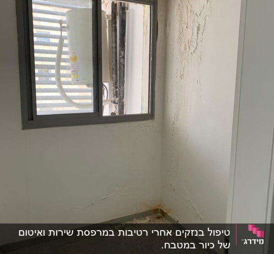 קיר עם רטיבות ותקרה מתקלפת ליד חלון